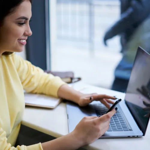 personne qui regarde le prix du vtc a paris sur son ordinateur et qui reserve avec son telephone